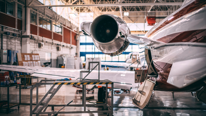 Small airplane parked in a hangar with a maintenance platform next to it